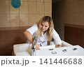Healthcare professional cleaning and preparing a bath with various knobs, controls, and a shiny faucet in a tiled medical facility room. 141446688