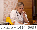 Medical Professional Eating: A woman in a white coat enjoys a snack during break, showcasing a moment of respite. The setting is casual and realistic. 141446695
