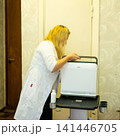 Medical professional prepares an ultrasound machine for a patient examination in a clinical setting. Focused care and advanced equipment. 141446705
