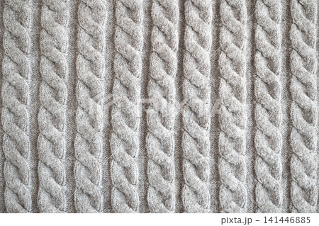 Close-up of grey cable knit sweater texture showing soft wool pattern and cozy winter fabric Close-up of grey cable knit sweater texture showing soft wool pattern and cozy winter fabric 141446885