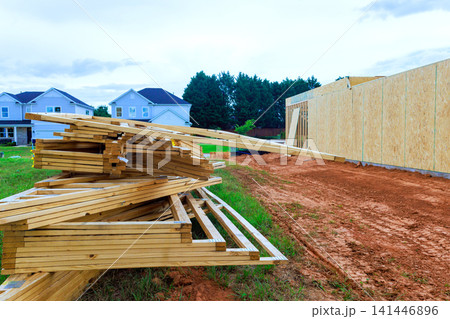 Workers prepare lumber beams framing materials at house construction site in suburban neighborhood Workers prepare lumber beams framing materials at house construction site in suburban neighborhood 141446896