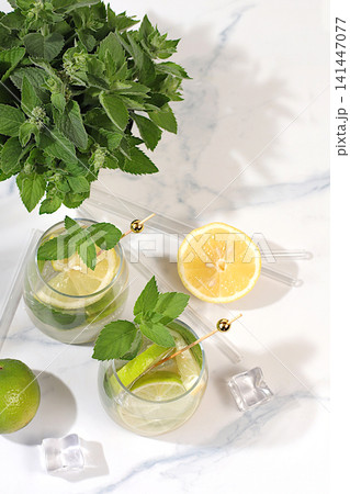 Icy homemade lemonade, juice or cocktail with mint, spearmint, lime, lemon and citrus, a refreshing summer drink recipe, a detox diet and weight loss concept, nonalcoholic mojito for energy Icy homemade lemonade, juice or cocktail with mint, spearmint, lime, lemon and citrus, a refreshing summer drink recipe, a detox diet and weight loss concept, nonalcoholic mojito for energy 141447077