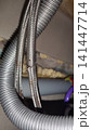 Damaged flexible hose with a metal braided sheath showing visible tears, corrosion, and signs of wear. 141447714