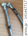 Close up of a worn braided water hose with rust and damaged protective metal mesh. 141447717