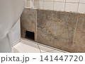 Damaged bathroom wall behind a toilet with missing tiles exposing a hidden hole in the surface. The defect may indicate water damage, plumbing issues, or the need for waterproofing inspection and 141447720