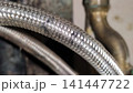 Close up of a worn braided water hose with rust and damaged protective metal mesh. 141447722