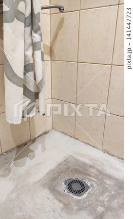 Preparing a shower area base during bathroom renovation, with cement mortar being used to level the floor surface and install a drainage system. Construction materials, plumbing elements, and wet room Preparing a shower area base during bathroom renovation, with cement mortar being used to level the floor surface and install a drainage system. Construction materials, plumbing elements, and wet room 141447723