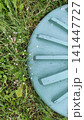 A plastic septic tank cover surrounded by fresh green grass in a residential outdoor area. Wastewater system access point, sanitation infrastructure, and landscape maintenance concept. 141447727