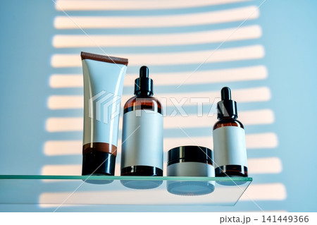 Cosmetics and serum bottles on glass shelf with light stripes 141449366