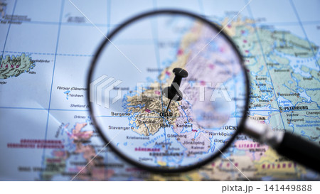 Close-up of a printed map with a magnifying glass highlighting Oslo 141449888