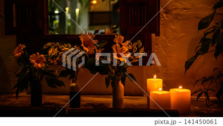Cozy candlelit floral arrangement by rustic wooden window with warm ambient lighting Cozy candlelit floral arrangement by rustic wooden window with warm ambient lighting 141450061