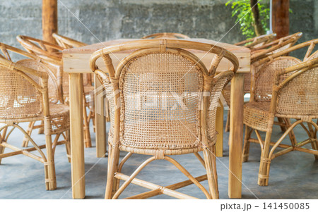 Cozy outdoor dining area with wooden table and wicker chairs on tropical villa patio Cozy outdoor dining area with wooden table and wicker chairs on tropical villa patio 141450085