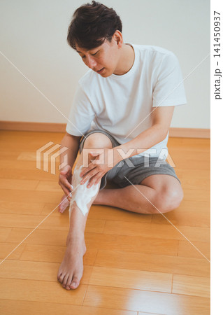 40代男性が床に座り脚のシェービング準備をするシーン 40代男性が床に座り脚のシェービング準備をするシーン 141450937