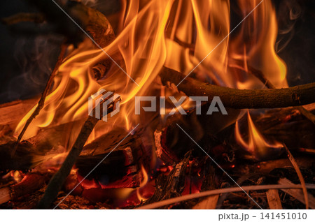 Close up of flame of bonfire burning in the wood. A large fire that is made outside to burn unwanted things, or for pleasure. Close up of flame of bonfire burning in the wood. A large fire that is made outside to burn unwanted things, or for pleasure. 141451010