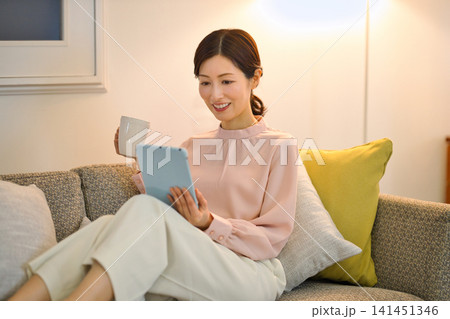 夜部屋でリラックスしてタブレットを見る40代の女性 夜部屋でリラックスしてタブレットを見る40代の女性 141451346
