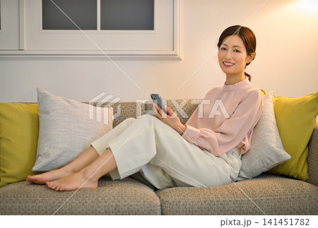 夜部屋でリラックスしてスマホを見る40代の女性 夜部屋でリラックスしてスマホを見る40代の女性 141451782
