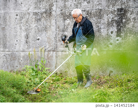 初夏に草刈り機で草刈りをする高齢男性 初夏に草刈り機で草刈りをする高齢男性 141452184