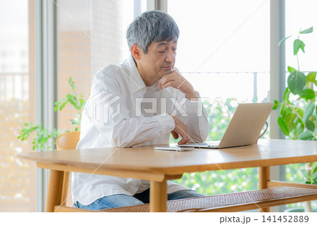 パソコンの画面を見て悩むシニア男性 パソコンの画面を見て悩むシニア男性 141452889
