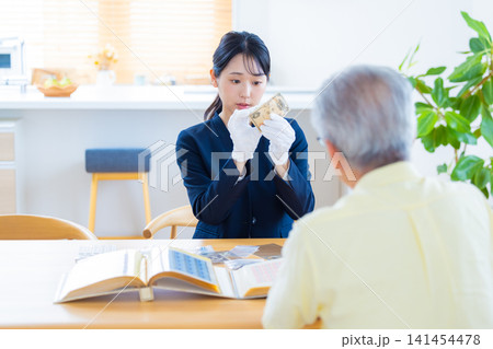 出張買取　訪問先で古銭の鑑定をしている鑑定士　 141454478