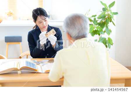 出張買取　訪問先で古銭の鑑定をしている鑑定士　 141454567
