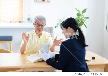 出張買取　自宅で切手や古銭の鑑定をしてもらっているシニア男性　 141454838