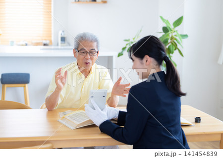 出張買取　自宅で切手や古銭の鑑定をしてもらっているシニア男性　 141454839