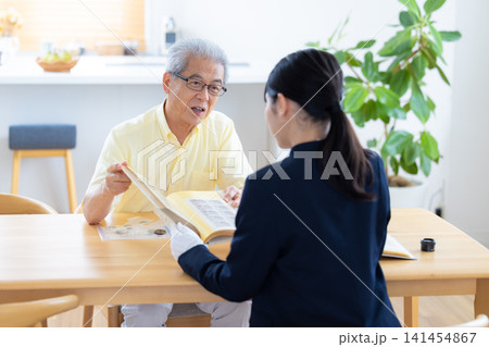出張買取 自宅で切手や古銭の鑑定をしてもらっているシニア男性 出張買取 自宅で切手や古銭の鑑定をしてもらっているシニア男性 141454867