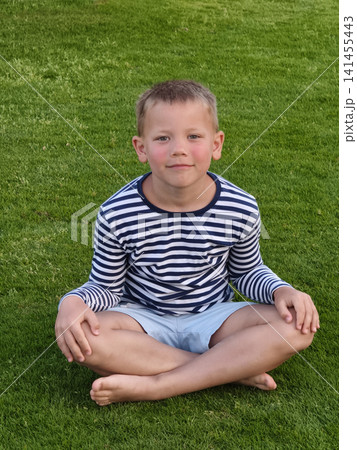 Young boy with a bright, open expression sits on lush green grass, his relaxed posture and curious gaze capturing the pure joy and carefree spirit of childhood amid nature s soft, vibrant backdrop. Young boy with a bright, open expression sits on lush green grass, his relaxed posture and curious gaze capturing the pure joy and carefree spirit of childhood amid nature s soft, vibrant backdrop. 141455443