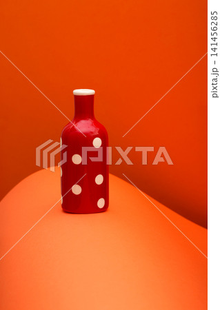 Red bottle on an abstract background of colored paper sheets 141456285