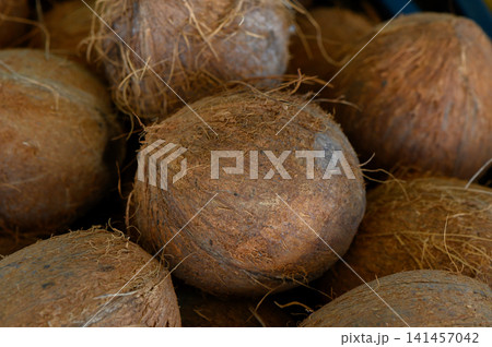 Coconuts resting together in a rustic market stall surrounded by earthy textures and vibrant colors Coconuts resting together in a rustic market stall surrounded by earthy textures and vibrant colors 141457042