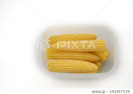 Freshly harvested sweet corn displayed in a clear container, showcasing vibrant yellow hue and inviting texture Freshly harvested sweet corn displayed in a clear container, showcasing vibrant yellow hue and inviting texture 141457539