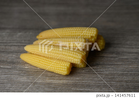 Delightful baby corn stacked on a rustic wooden table ready for a tasty dish 141457611