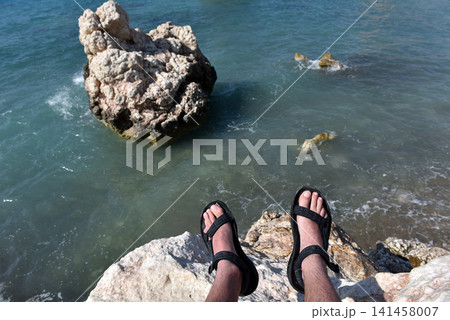 Hiker feet in sandals resting on coastal cliffs overlooking Petra tou Romiou, Cyprus Hiker feet in sandals resting on coastal cliffs overlooking Petra tou Romiou, Cyprus 141458007