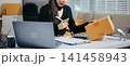 Asian e-commerce entrepreneur live streaming with laptop and parcel boxes. Online seller, content creator, social media marketing, remote business 141458943