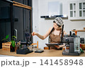 Focused Asian female barista taking stock and managing inventory with a clipboard at a modern cafe counter. 141458948