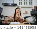 Young Asian female barista preparing fresh roasted coffee beans in a modern cafe kitchen with professional espresso equipment. 141458958