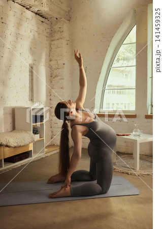 Flexible young pregnant woman performing side stretch on yoga mat at home Flexible young pregnant woman performing side stretch on yoga mat at home 141459325