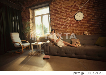 Pregnant woman relaxing on sofa during quiet day at home Pregnant woman relaxing on sofa during quiet day at home 141459349