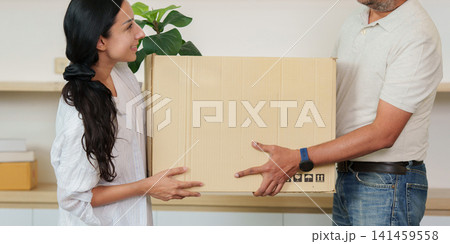 Indian couple carrying cardboard box together while moving into new home 141459558