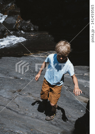 Child Exploring Rocky Terrain by a Stream Child Exploring Rocky Terrain by a Stream 141459565