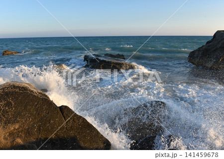 Sea stack on a dark sand shore with white waves at sunset, Cyprus Sea stack on a dark sand shore with white waves at sunset, Cyprus 141459678