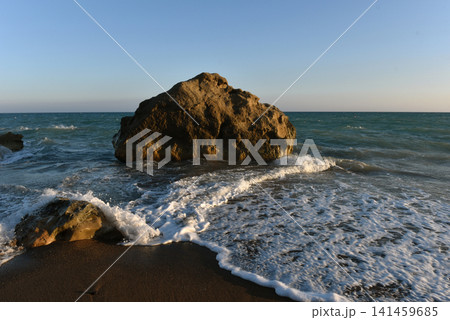 Sea rock surrounded by crashing sea foam on a sandy beach at golden hour, Cyprus Sea rock surrounded by crashing sea foam on a sandy beach at golden hour, Cyprus 141459685