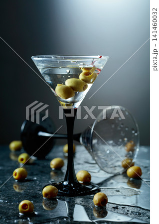 Green olives and glass of martini on a black stone table. 141460032