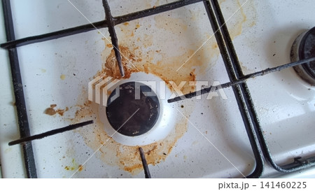 Close up of a dirty white gas stovetop with heavy brown and orange grease stains around a single burner and metal grate... Close up of a dirty white gas stovetop with heavy brown and orange grease stains around a single burner and metal grate... 141460225