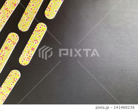 Five bright green floral patterned nail files arranged diagonally on a dark gray background with ample negative space.. Five bright green floral patterned nail files arranged diagonally on a dark gray background with ample negative space.. 141460238