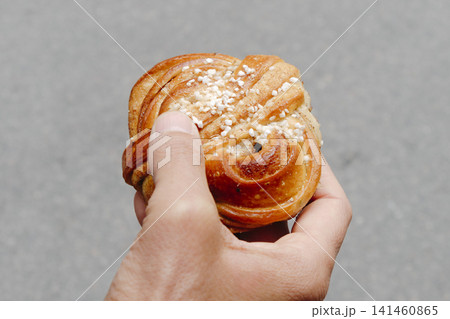 a close-up of a swedish kanelbulle held by a man a close-up of a swedish kanelbulle held by a man 141460865