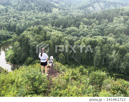 A woman with a dog came to the top and watch the panorama landscape valley. River, forest, years, gorge adventure A woman with a dog came to the top and watch the panorama landscape valley. River, forest, years, gorge adventure 141461722