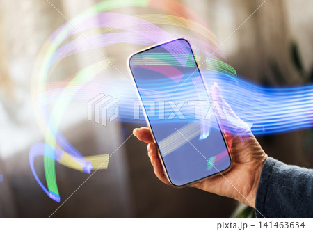 Hand holding smartphone with colorful light trails in motion, showcasing modern technology and digital connectivity against a blurred background Hand holding smartphone with colorful light trails in motion, showcasing modern technology and digital connectivity against a blurred background 141463634