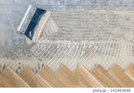 Oak herringbone parquet flooring installation with adhesive on concrete subfloor top view Oak herringbone parquet flooring installation with adhesive on concrete subfloor top view 141463698