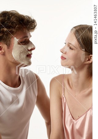 Side portrait of young woman looking at boyfriend wearing full facial mask 141463807